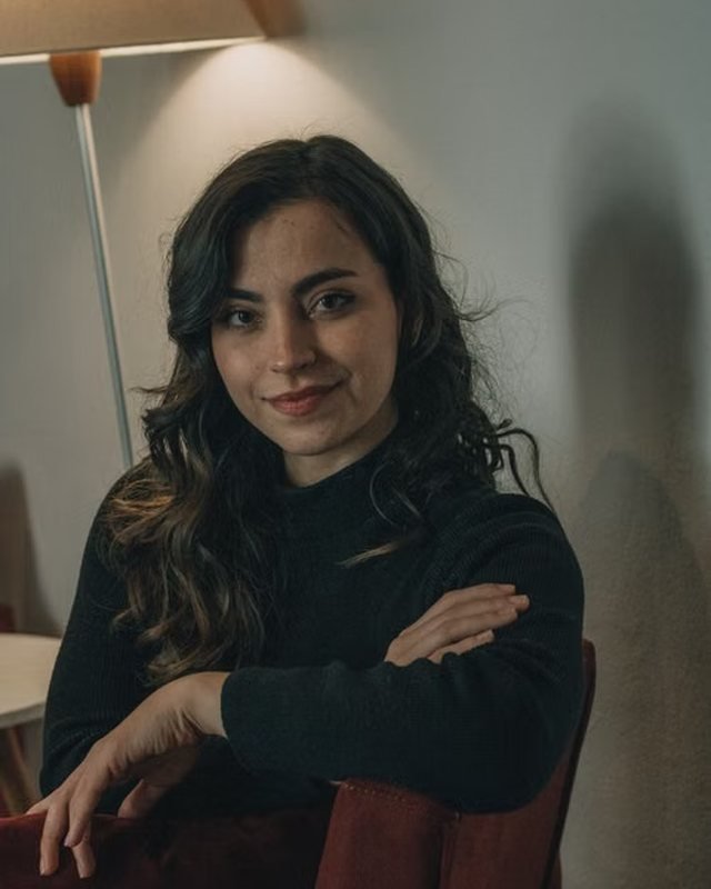 Portrait of Elena Ward, seated by a lamp in warm light